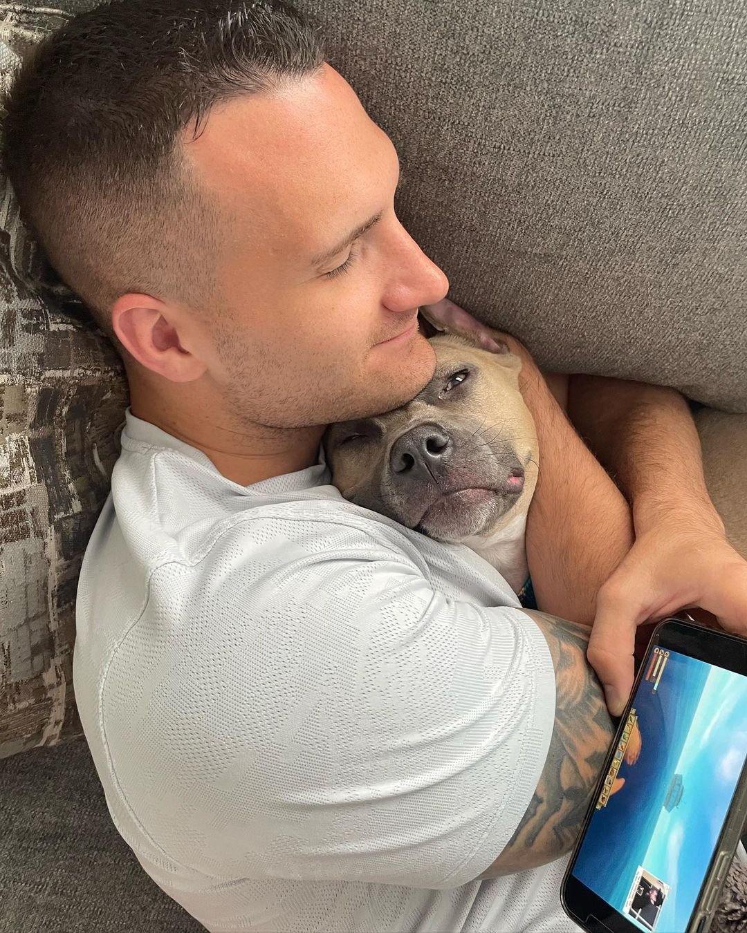 man lying with pit bull on couch